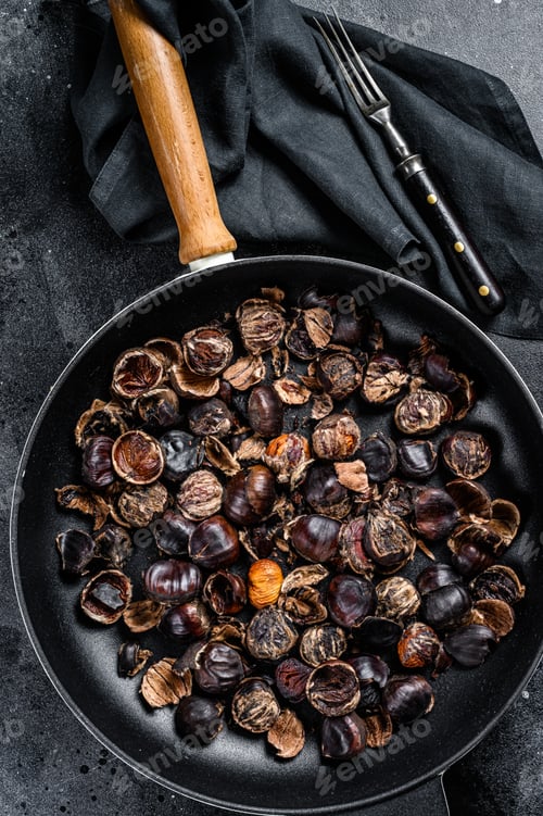 Preview: Roast grilled chestnuts on a wooden table. Black background. Top view