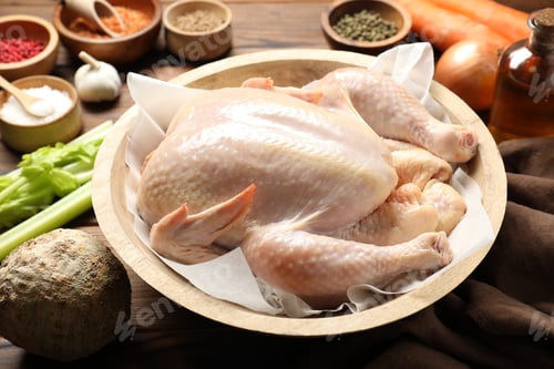 Preview: Fresh raw turkey in bowl and different products on table, closeup