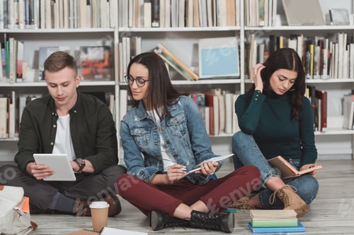 Preview: multicultural friends studying and sitting on floor in library