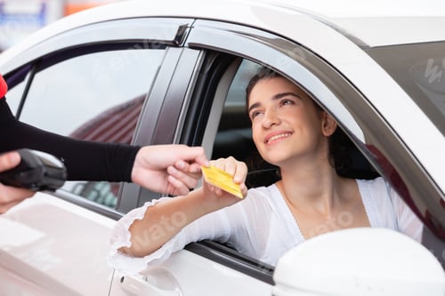 Preview: happy woman in car paying credit card after refuel car spending instead of cash at gas station.