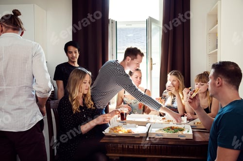 Preview: Group of friends chatting over drinks and pizza at home