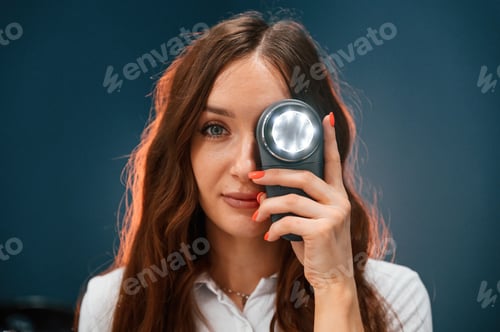 Preview: Woman cosmetologist is holding device with light