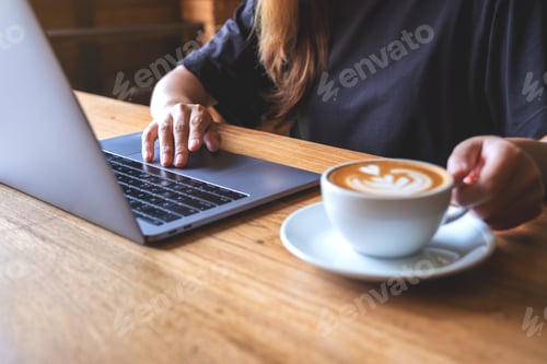 Preview: Closeup image of a businesswoman drinking coffee while working on laptop computer