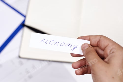 Preview: Closeup shot of the word economy written on a piece of paper in a person's hand