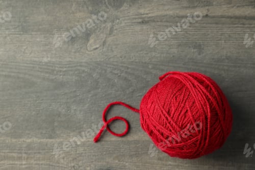 Preview: Red ball of yarn on gray wooden background.