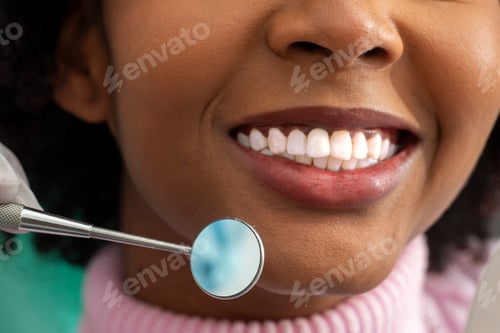 Preview: Patient smiling while dentist holds dental mirror in clinic