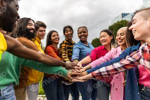 Preview: Young multiracial community of friends having fun stacking hands together outdoor