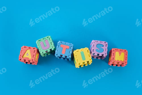 Preview: Word Autism on puzzle cubes on blue background.