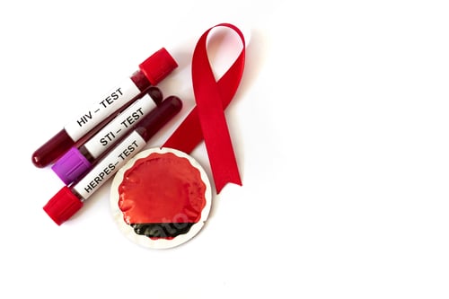 Preview: AIDS ribbon with blood tubes from sexually transmitted disease tests and condom on white background