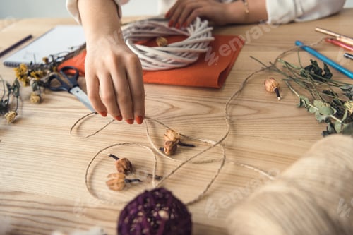 Preview: cropped view of female hands holding twine and white wreath at workplace
