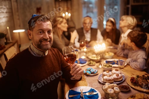 Preview: Happy Jewish man celebrating Hanukkah with his extended family at dining table