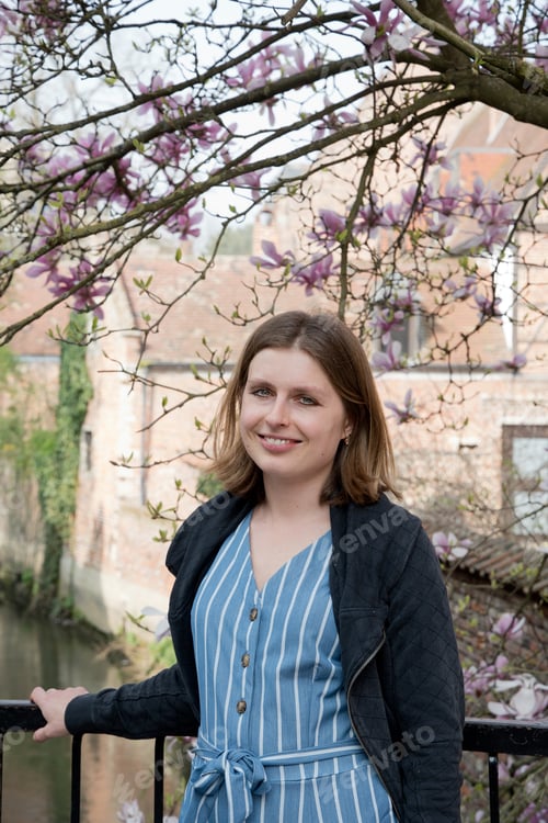Preview: beautiful young caucasian girl stands under blooming magnolia and smiles in spring
