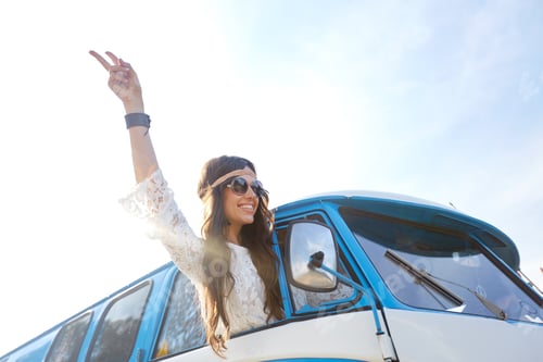 Preview: happy hippie woman showing peace in minivan car