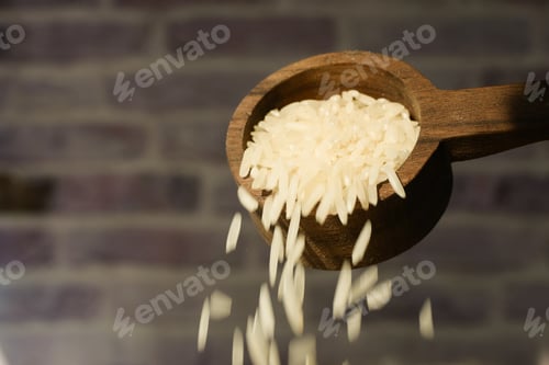 Preview: Raw white rice pouring from a wooden spoon