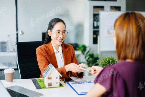 Preview: Smiling real estate agent showing calculator to client with house model. Perfect for property