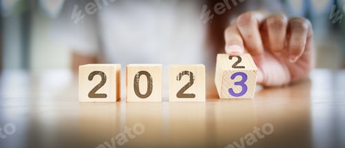 Preview: 2023 New year concept. Fingers turning the block from 2022 to 2023 by woman's hand. Graphic banner