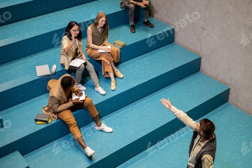 Preview: Young teacher pointing at student with raised hand