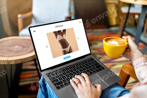 Visualização: Senhora usando laptop com loja de moda na tela, comprando roupas íntimas, sentada no café, navegando na internet