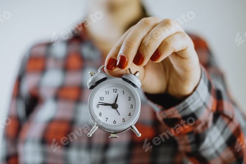 Preview: Time management. Small alarm clock in female hands