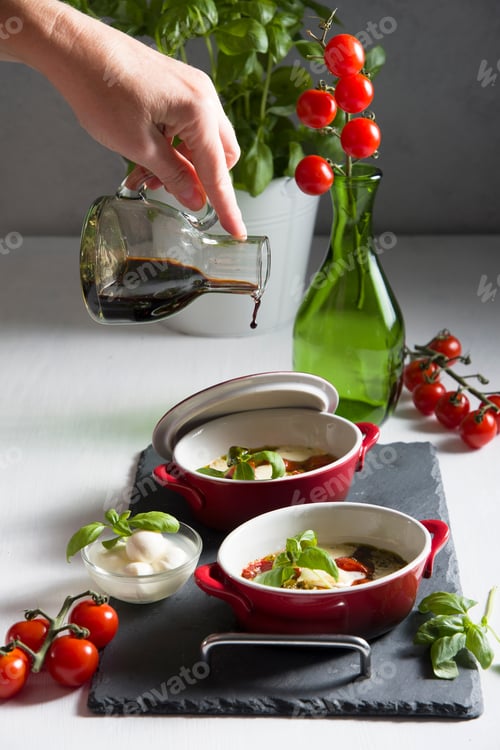 Preview: Italian caprese salad, baked cherry tomatoes, mozzarella and basil on a white table, still life