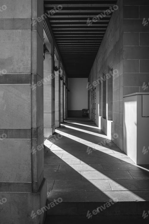Preview: Grayscale shot of an outer corridor with shadows of beams