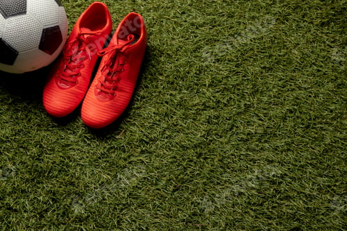 Preview: Composition of football and shoes over sports stadium and copy space