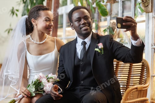Preview: Young black couple as bride and groom taking selfie photo