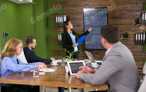 Preview: Business woman in a conference room holding a presentation with charts on tv screen