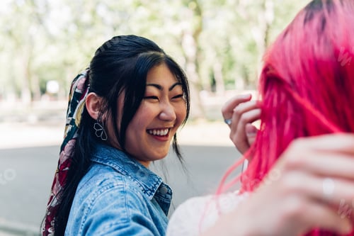 Preview: Happy Asian woman hugging girlfriend in park