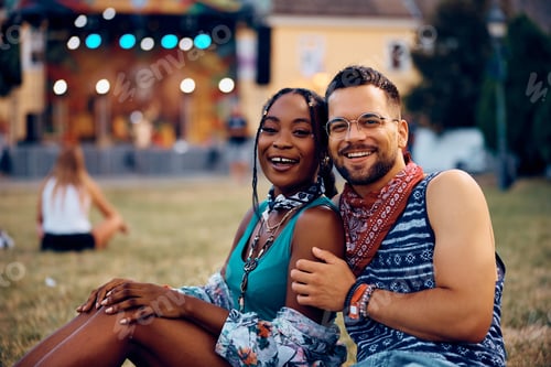 Preview: Happy multiracial couple attending summer music festival and looking at camera.