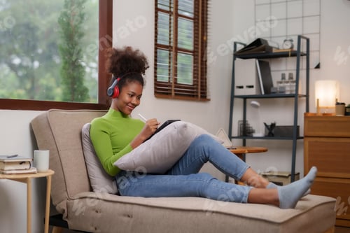 Preview: Cute young woman using tablet entertainment relaxing at home.