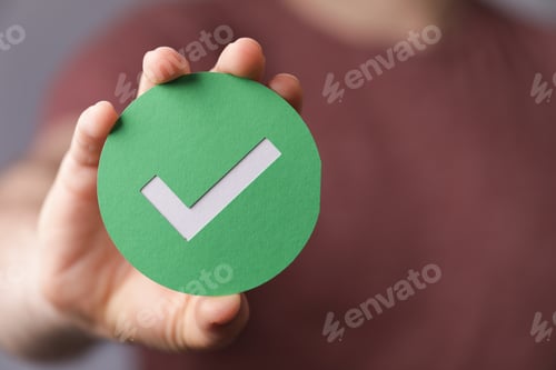 Preview: Sign of the checkmark made of paper in the hands of a man