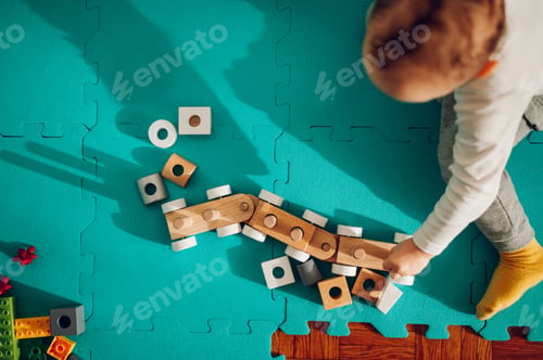 Preview: Top view of a youngster playing a fun game with an educational Montessori toy at home.