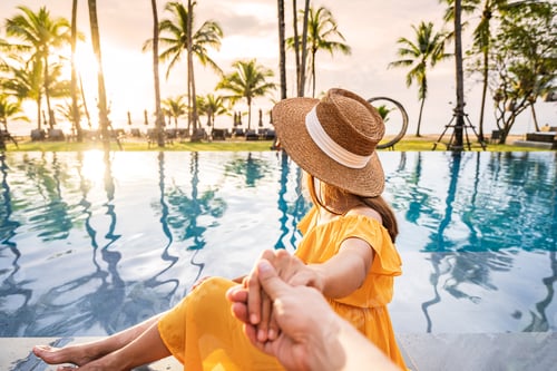 Preview: Young couple traveler relaxing and enjoying the sunset by a tropical resort pool