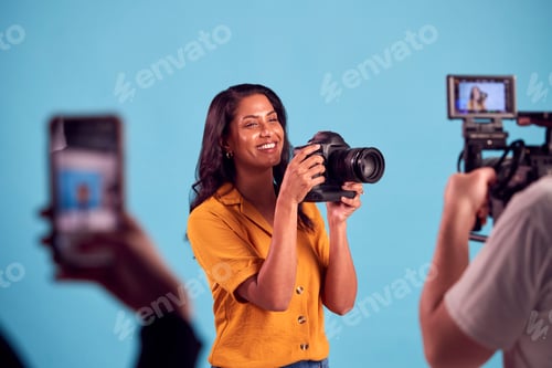 Preview: Mature Woman In Studio On Shoot With Video And Mobile Phone Holding DSLR