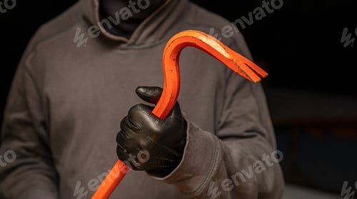 Preview: Burglar holding a crowbar, black background, closeup view