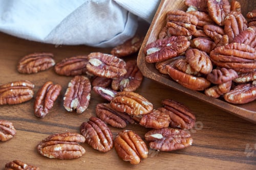 Preview: pecan nuts in wood bowl on old brown table, selective focus. top view. Healthy food and snack.