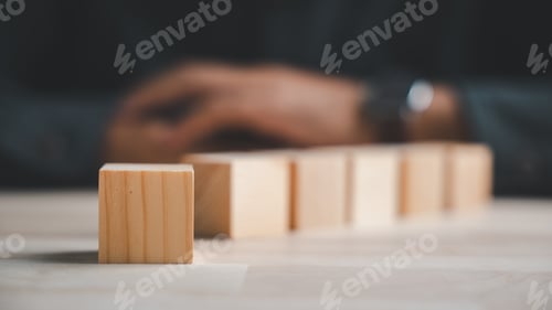 Preview: A close-up of a single wooden block on a light wood table, with blurred wooden blocks and a