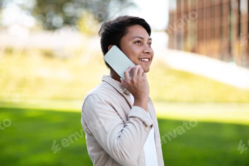 Preview: Young asian entrepreneur talking on phone while walking by park
