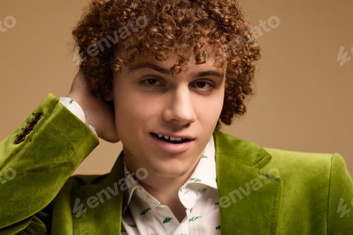 Preview: Curly-haired teenager showcases vibrant green velvet blazer in studio setting