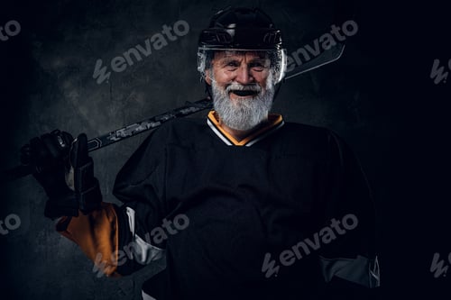 Preview: Joyful elderly hockey player with hockey stick dressed in uniform