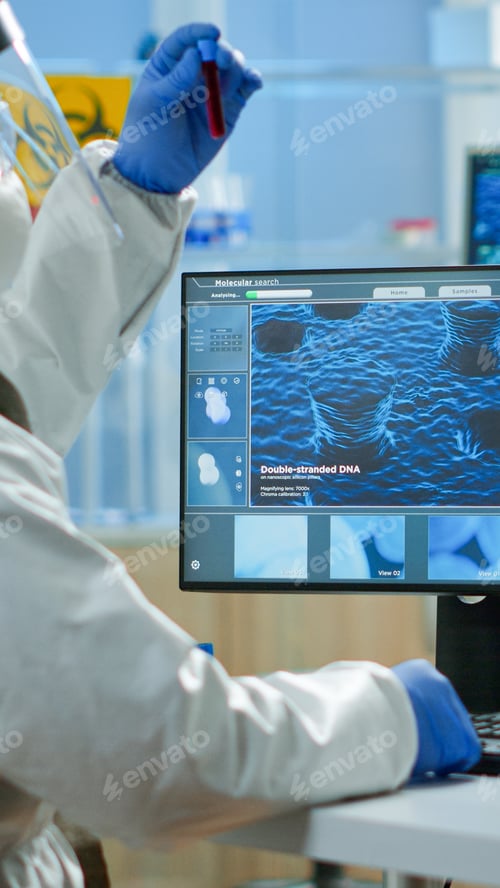 Preview: Back view of chemist man in coverall typing on computer analysing vaccine evolution