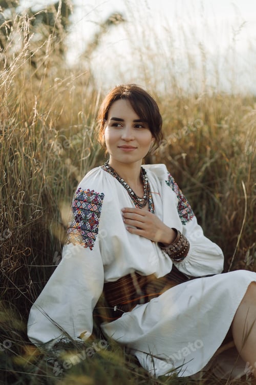 Vista previa: Young woman in traditional national embroidered shirt and skirt on nature at sunset.