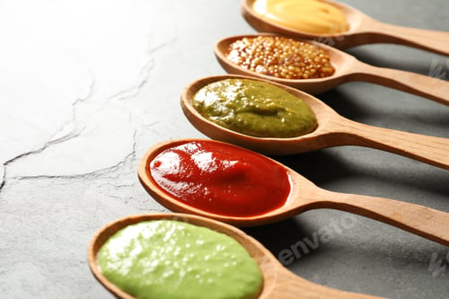 Preview: Set of wooden spoons with different delicious sauces on grey table, closeup