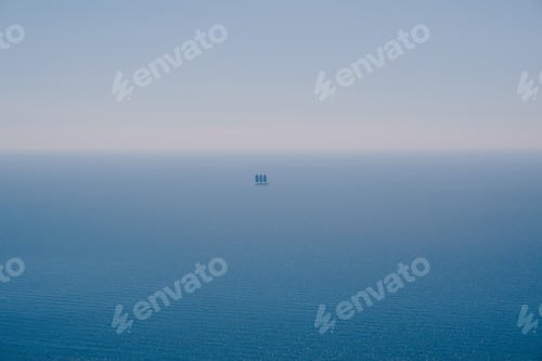 Preview: Yacht with three sails floats on the blue sea on the horizon