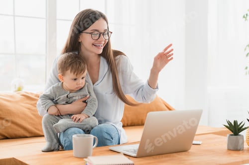 Preview: Happy young single mother having video call conference online on laptop holding toddler