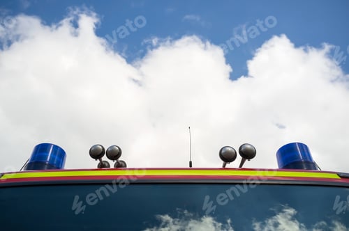 Preview: Fire engine with signal lamps and a siren, against the blue sky and white clouds