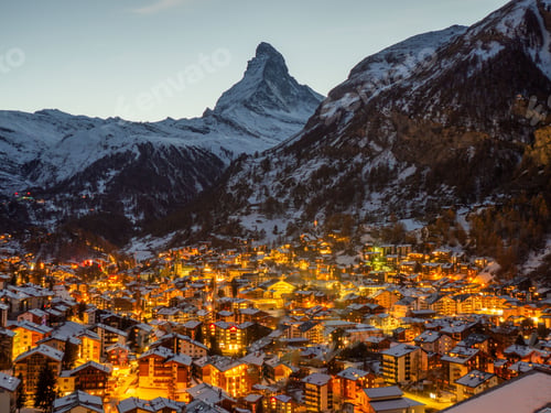 Preview: a town in the night with snow on the ground and the mountain range in the
