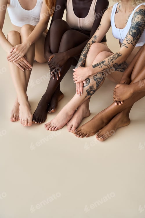Preview: Young diverse women wearing underwear sitting on beige showing smooth legs.