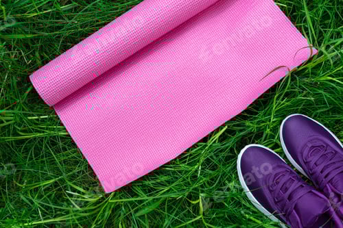 Preview: Sports shoes sneakers and yoga mat on fresh green grass. Sport equipment top view